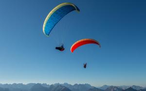 twee paragliders vliegen in de lucht over bergen bij Apartment De Gasperi in Serrone