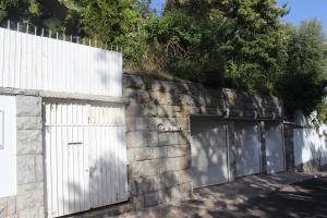 a stone wall with two garage doors and a fence at Cascais Jasmim Doce in Cascais