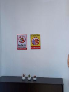 three signs on a white wall above a table at The Warm House in Ban Komo Sip Paet