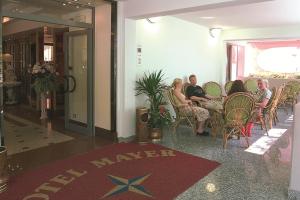Eine Gruppe von Menschen sitzt an einem Tisch in einer Lobby in der Unterkunft Hotel Mayer in Bibione + 137 Fotos