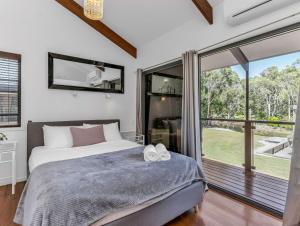 een slaapkamer met een bed en een groot raam bij Lennox Coastal Retreat - resort-style home w. pool in Lennox Head +47 foto's