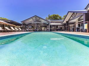 een zwembad met stoelen en een gebouw bij Lennox Coastal Retreat - resort-style home w. pool in Lennox Head