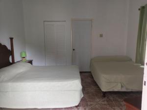a bedroom with two beds and a door to a room at Polish Princess Guest House in Port Antonio