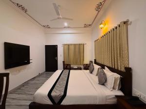 a bedroom with a large bed and a flat screen tv at Atulya Niwas in Udaipur