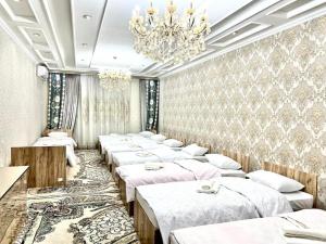 een rij bedden in een kamer met een kroonluchter bij Hostel Marshal in Termiz