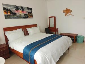 a bedroom with a large white bed with a blue blanket at Zawadi Apartment in Dar es Salaam +6 photos