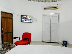 a room with a red chair and a tv on the wall at Glory Farm in Vadāli