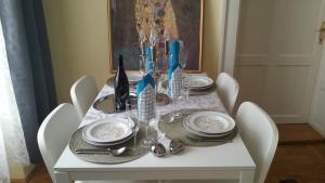 a white table with white chairs and a table with plates and dishes at BMG Apartment in Budapest