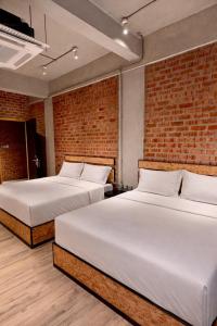 two beds in a room with a brick wall at Brick Box Family Hotel Ipoh in Ipoh