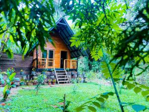 a wooden house with a porch and a yard at Sigiriya Carpenter Cottage in Sigiriya