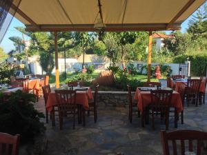 a restaurant with tables and chairs under a pavilion at Vontzos Hotel in Achladies