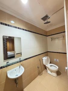 een badkamer met een toilet, een wastafel en een spiegel bij Ariyani Hotel Dungun in Gua Sai +7 foto's