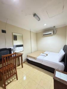 een slaapkamer met een bed, een bureau en een tv bij Ariyani Hotel Dungun in Gua Sai