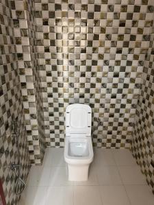 a bathroom with a toilet in a tiled wall at Hari Vatika in Varanasi