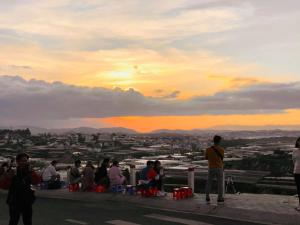 a group of people sitting on a ledge looking at the sunset at Gold Villa in Trai Mat