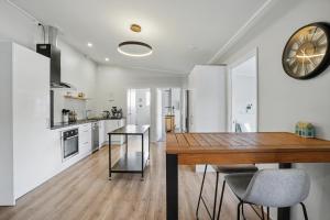 een keuken met een houten tafel en een klok aan de muur bij The Upper Rooms in Nelson