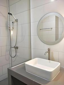 een witte badkamer met een wastafel en een spiegel bij Pannara Hotel in Lop Buri