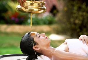a woman laying in a pool with a bowl of honey at Somatheertham Resort in Kovalam