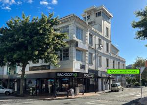een gebouw aan een straat met een boom en een straatnaambord bij The Upper Rooms in Nelson