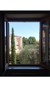 a window with a view of a tree and a building at Affittacamere Dal Falco in Pienza