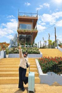 Een vrouw staat met een koffer op de trap. bij Han San Homestay Măng Đen in Kon Plong