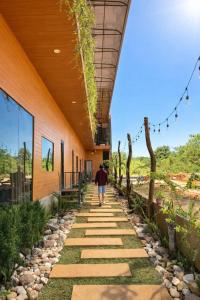 a person walking down a walkway next to a building at Han San Homestay Măng Đen in Kon Plong +52 photos