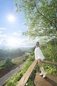 een vrouw die bovenop een houten hek staat bij Han San Homestay Măng Đen in Kon Plong