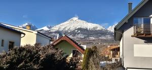 a snow covered mountain in the distance behind houses at INLE Homestay in Nová Lesná +12 photos