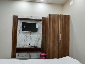 a bedroom with a tv and a wooden cabinet at Hotel Sobhagyam in Kekri
