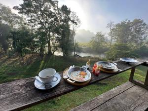 a table with plates of food and a cup of coffee at Vela Resort Umphang in Ban Mae Klong Mai