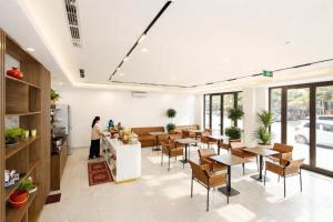 a woman standing in a restaurant with tables and chairs at The Sun Hotel - Ninh Bình in Kỳ Vĩ