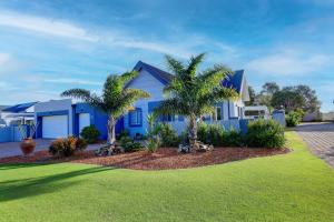 a blue house with palm trees in front of it at Albatross @ Kingswood in George
