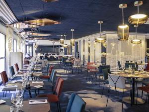a dining room with tables and chairs and chandeliers at Hotel Mercure Blois Centre in Blois