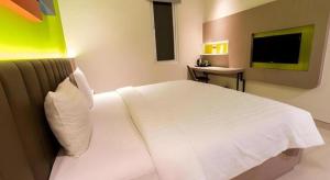una camera da letto con un letto bianco e una televisione di Zoom Dharmahusada Hotel a Surabaya