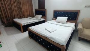 een kamer met 2 aparte bedden en een stoel bij Hotel Golden Bird in Dhaka
