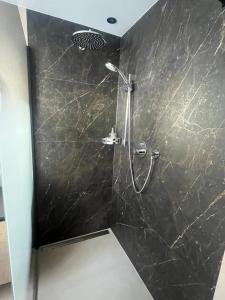 een badkamer met een douche en een zwarte marmeren muur bij Haus Schaller in Valle Di Casies