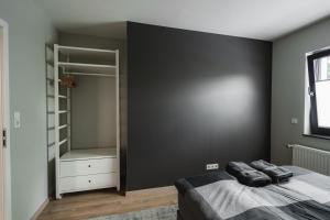 een slaapkamer met een zwarte muur en een bed bij NürbLife Hotel in Nürburg