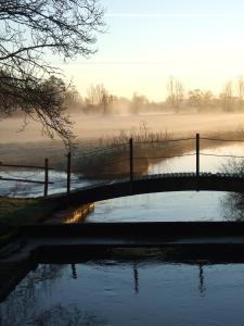 a body of water with a fence next to a field at Moulin de la Fosse Soucy in Maisons