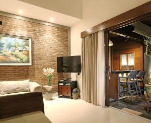 a living room with a television and a brick wall at HomeSix Bali in Uluwatu