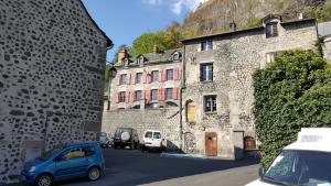 a blue car parked in front of an old building at Relais des castors in Murat