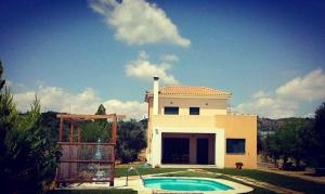 a house with a swimming pool in front of it at Orfeas Villa in Kotróni