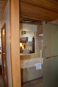 a bathroom with a tub and a bed in a mirror at Angkorian Hostel in Phumi Ta Phul