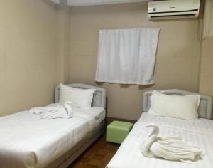 twee bedden in een kamer met zwanen handdoeken erop bij Pandora Motel in Yangon