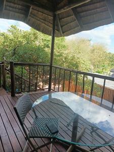 a glass table on a wooden deck with a chair at Do Drop In in Hoedspruit