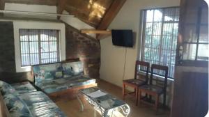 a living room with a couch and chairs and a tv at Do Drop In in Hoedspruit