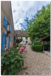 una casa con flores rosas al lado de un edificio en La Cuverie du Château, en Corcelles-les-Arts