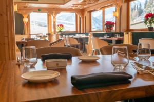 a wooden table with plates and glasses on it at Grifone Dolomiti Resort in Arabba