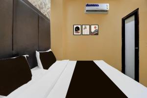 una camera da letto con un letto bianco e nero e un condizionatore di Hotel O Lotus Inn a Faridabad