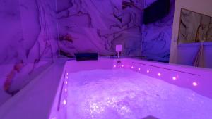 a purple room with a tub with lights in it at MagicSpa Gold in Chilly-Mazarin