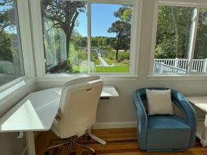 a office with a desk and a chair and windows at Serene waterfront getaway in Mashpee